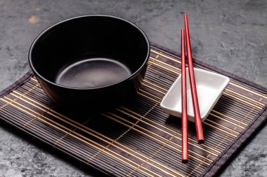 Boş Japon yemekleri. Çin noodle veya Tay çorba için siyah seramik kase bamkuk halıya yatıyor. Soya sosu ve kırmızı Çin için beyaz saucepot bir siyah arka plan üzerine yapışır. Üstten görünüm, kopya alanı