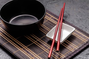Boş Japon yemekleri. Çin noodle veya Tay çorba için siyah seramik kase bamkuk halıya yatıyor. Soya sosu ve kırmızı Çin için beyaz saucepot bir siyah arka plan üzerine yapışır. Üstten görünüm, kopya alanı