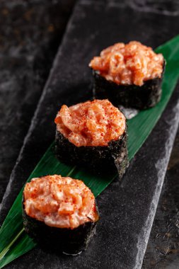 Somon bir bambu yaprak ve siyah taş mazisi ile gunkan Maki Sushi ile. Bambu hasır. kırmızı Çin sopa. Sushi Menüsü. Japon yemekleri. eğilim renk 2019 mercan. arka plan resmi