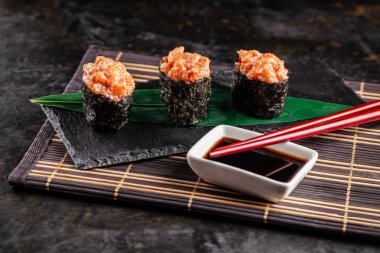 Somon bir bambu yaprak ve siyah taş mazisi ile gunkan Maki Sushi ile. Bambu hasır. kırmızı Çin sopa. Sushi Menüsü. Japon yemekleri. eğilim renk 2019 mercan. arka plan resmi