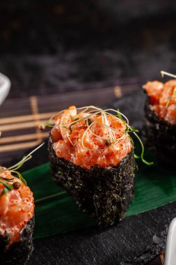 Somon bir bambu yaprak ve siyah taş mazisi ile gunkan Maki Sushi ile. Bambu hasır. kırmızı Çin sopa. Sushi Menüsü. Japon yemekleri. eğilim renk 2019 mercan. arka plan resmi