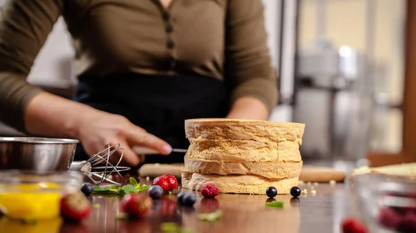 The pastry chef prepares a biscuit cake in the home kitchen or in a restaurant. The concept of the process of making cakes for restaurants, cafes and bars. on the photo the girl hands cuts a biscuit