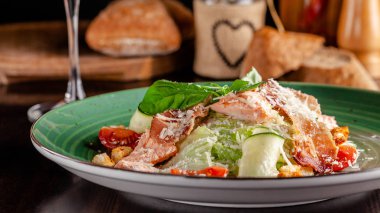 İtalyan mutfağı kavramı. Sezar salatası somon, marul mix, kiraz domates ve parmesan peyniri ile. Bir bardak beyaz şarap masanın üzerinde. Restoranda yemekler sunan