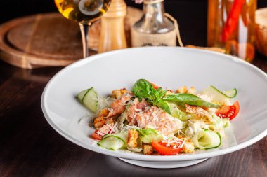 İtalyan mutfağı kavramı. Sezar salatası somon, marul mix, kiraz ve parmesan peyniri ile. Bir bardak beyaz şarap masanın üzerinde. Restoranda yemekler sunan. kopya alanı
