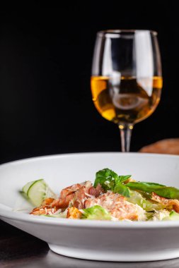 İtalyan mutfağı kavramı. Sezar salatası somon, marul mix, kiraz ve parmesan peyniri ile. Bir bardak beyaz şarap masanın üzerinde. Restoranda yemekler sunan. kopya alanı