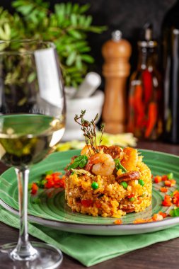 European Spanish cuisine. Paella with shrimps, chicken and coblas chorizo. White wine on the table. Closeup background image. Beautiful serving dishes in the restaurant. copy space clipart