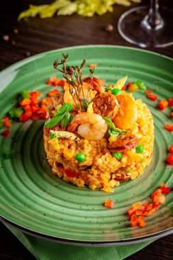 European Spanish cuisine. Paella with shrimps, chicken and coblas chorizo. White wine on the table. Closeup background image. Beautiful serving dishes in the restaurant. copy space clipart