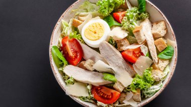 Ev yapımı Sezar salata tavuk, tavuk yumurta, domates, kaşar peyniri, marul Mix ve Sezar sos ile. gri arka plan üzerinde çanağı. Üstten Görünüm, kopya alanı