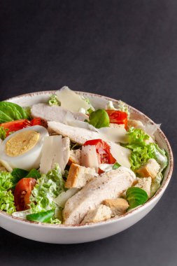 Ev yapımı Sezar salata tavuk, tavuk yumurta, domates, kaşar peyniri, marul Mix ve Sezar sos ile. gri arka plan üzerinde çanağı. Üstten Görünüm, kopya alanı