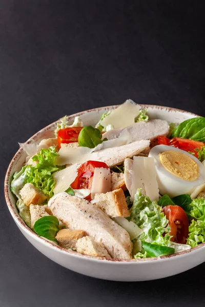 Homemade Caesar Salad with Chicken, Chicken Egg, Cherry Tomatoes, Parmesan Cheese, Lettuce Mix and Caesar Sauce. dish on gray background. Top view, copy space