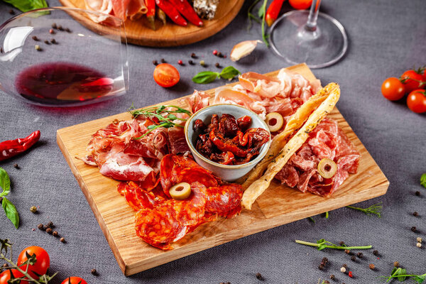 Italian food. Assortment of appetizers for a large company in a restaurant. Different types of smoked meat, sausages and cheeses. a glass of cool wine.