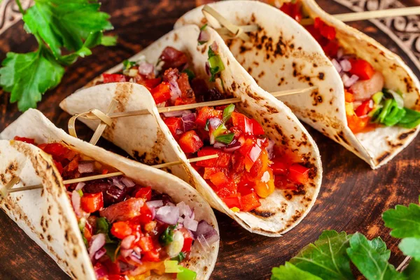 Concept of Mexican cuisine. Mexican appetizer Tacos with vegetables, beans, paprika, chilli peppers on fried unleavened bread cakes. Taco for veterinarians. Background image.