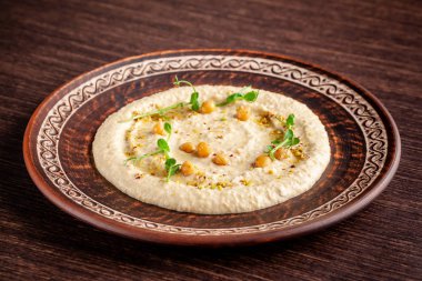 Arap mutfağı kavramı. Oryantal humus ızgara susam ve antep fıstığı ile. Ahşap bir masa üzerinde kırmızı bir seramik tabak içinde bir restoranda bir yemek. Üstten Görünüm, kopya alanı