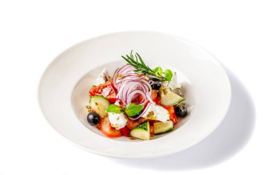 Yunan mutfağı kavramı. Salata domates, salatalık, biber, zeytin ve beyaz peynir. zeytin yağı ile giyinmiş ve taze fesleğen ile dekore edilmiştir. Beyaz bir arka plan üzerinde beyaz tabak.