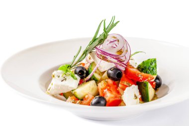 Yunan mutfağı kavramı. Salata domates, salatalık, biber, zeytin ve beyaz peynir. zeytin yağı ile giyinmiş ve taze fesleğen ile dekore edilmiştir. Beyaz bir arka plan üzerinde beyaz tabak.