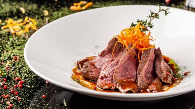 Avrupa mutfağı. Orta pişmiş rosto ile marine edilmiş Dana. Kavurma derecesi. Şef sığır eti zeytinyağı dökülen. Beyaz bir plaka restoran yemekleri sunan. arka plan resmi, kopya alanı