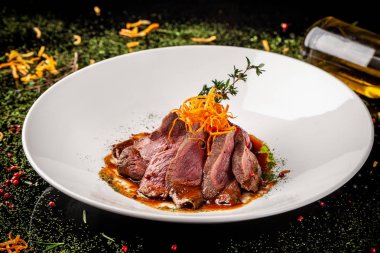 Avrupa mutfağı. Orta pişmiş rosto ile marine edilmiş Dana. Kavurma derecesi. Şef sığır eti zeytinyağı dökülen. Beyaz bir plaka restoran yemekleri sunan. arka plan resmi, kopya alanı