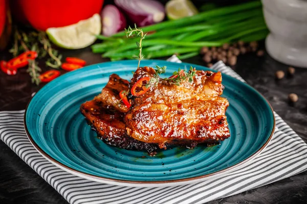 American cuisine. Grilled marinated pork ribs on a blue plate with shrimp and spicy chili in barbecue sauce. Background image. copy space
