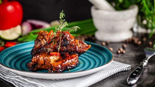 American cuisine. Grilled marinated pork ribs on a blue plate with shrimp and spicy chili in barbecue sauce. Background image. copy space