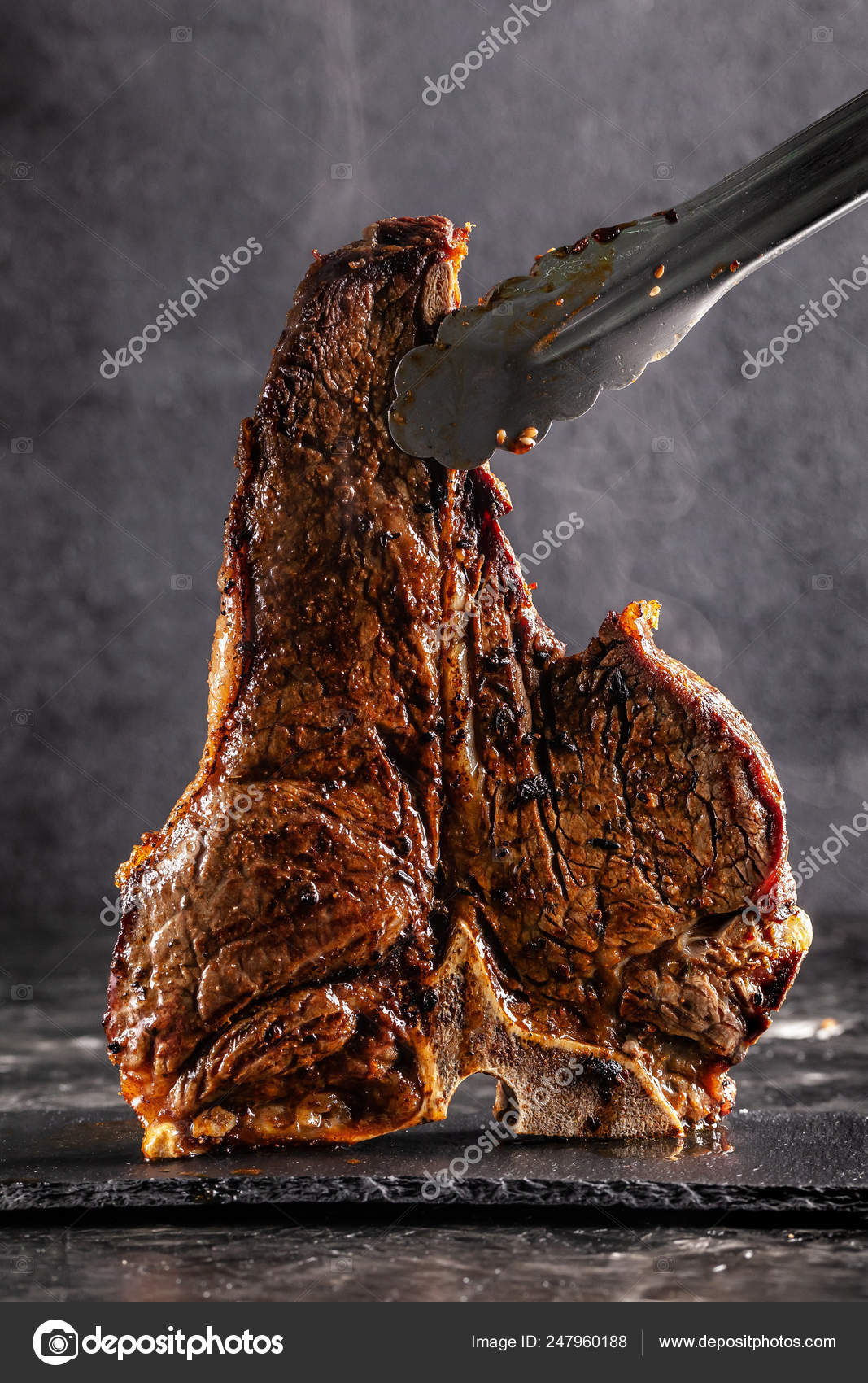 Large beef roast Tbone steak with smoke. Head chef holding steak meat