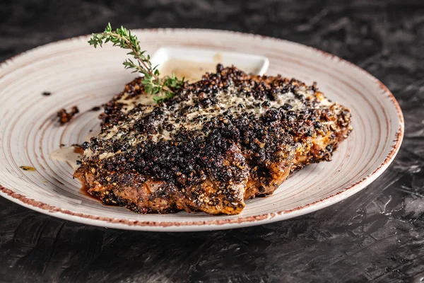 The concept of American cuisine. Fried, juicy pork steak in black pepper with thyme and white cheese sauce on a white ceramic dish. Serving dishes in the restaurant. copy space