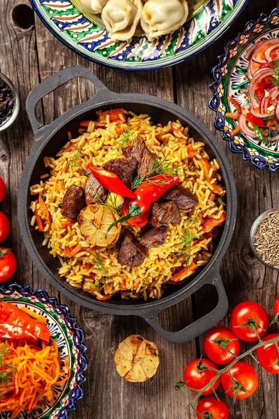 Cuisine orientale ouzbèke traditionnelle. Table de famille ouzbèke de différents plats dans les plats nationaux pour les vacances du Nouvel An. L'image de fond est une vue de dessus, l'espace de copie, la couche plate — Photo