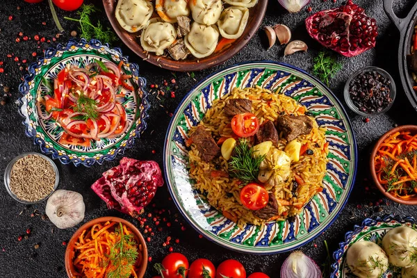 Cuisine orientale ouzbèke traditionnelle. Table de famille ouzbèke de différents plats dans les plats nationaux pour les vacances du Nouvel An. L'image de fond est une vue de dessus, l'espace de copie, la couche plate — Photo