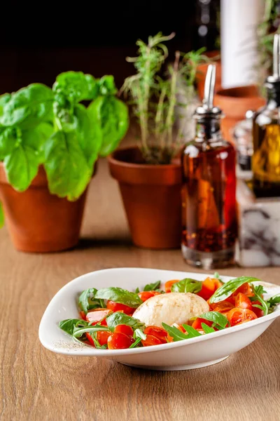 Концепция итальянской кухни. Салат капрезе с помидорами черри, ругулой и базиликовой смесью салата и сыром моцарелла. Подача блюд в белой тарелке в ресторане. фоновое изображение . — стоковое фото
