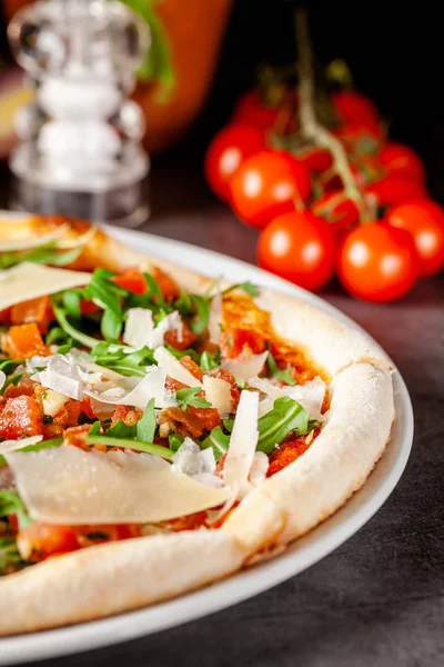Concept de cuisine italienne. Pizza fine aux côtés épais avec saumon, roquette et tomates cerises et parmesan. Le chef remplit la pizza d'huile d'ail. Image de fond . — Photo