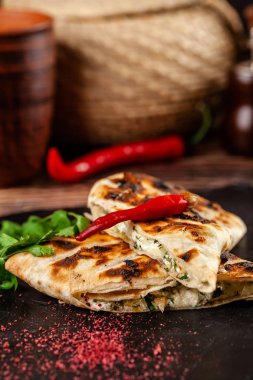 Gürcü mutfağı kavramı. Suluguni peynir ve Salantro ile pişmiş pide. Siyah taş mazisi yemekleri sunan. Ahşap bir arka plan üzerinde. kopya alanı