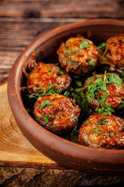The concept of Georgian cuisine. Baked mushrooms champignons with meat and cilantro. Serving dishes in a restaurant in a plate made of red clay. On a wooden background. copy space — Stock Photo, Image