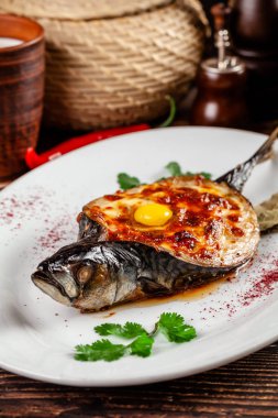 Gürcü mutfağı kavramı. Fırında Balık uskumru Adzhar. Ahşap bir masa üzerinde beyaz bir tabakta Gürcü restoranda yemekler sunan. Arka plan görüntüsü. kopya alanı