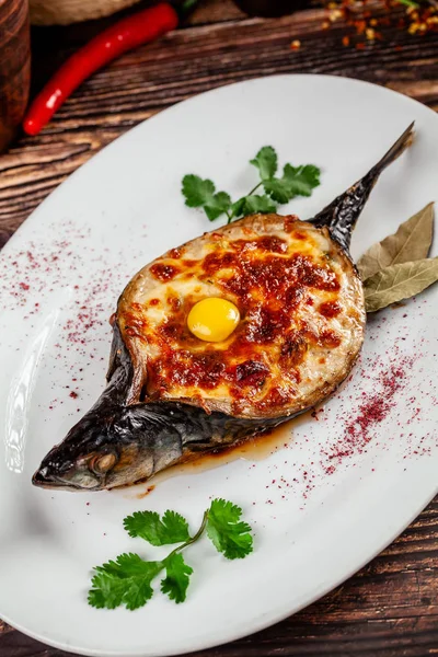 Il concetto di cucina georgiana. Pesce al forno Sgombro Adzhar. Servire piatti nel ristorante georgiano su un piatto bianco, su un tavolo di legno. Immagine di sfondo. copia spazio — Foto Stock