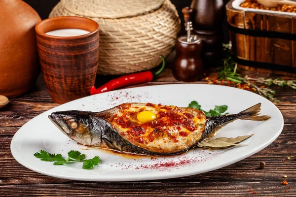 Begreppet georgiska köket. Ugnsbakad fisk makrill Coolsoldier07. Serveringsfat i georgisk restaurang på en vit platta, på ett träbord. Bakgrundsbild. kopia utrymme — Stockfoto