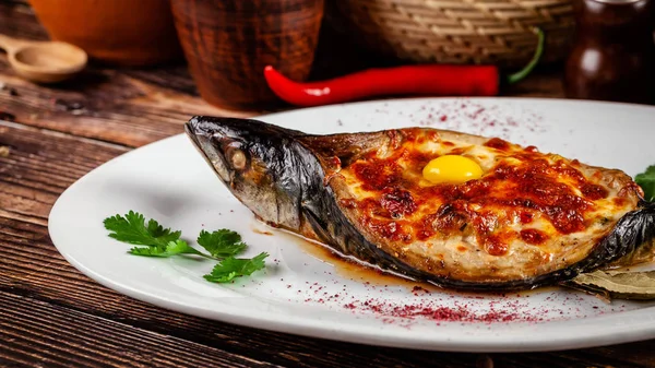 Das Konzept der georgischen Küche. gebackener Fisch Makrele adzhar. serviert Gerichte im georgischen Restaurant auf einem weißen Teller, auf einem Holztisch. Hintergrundbild. Kopierraum — Stockfoto