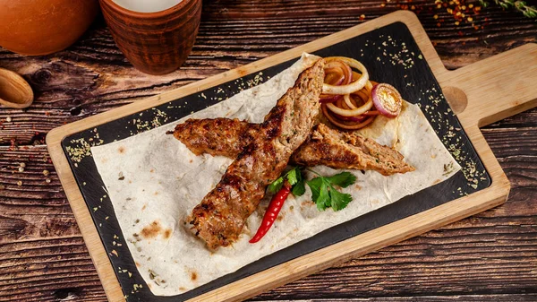 Gürcistan mutfağı kavramı. Et ve baharattan yapılmış sulu lula kebabı. Pide üzerindeki bir restoranda, tahta bir tahtanın üzerinde bulaşık servisi yapmak. Boşluğu kopyala, arkaplan resmi