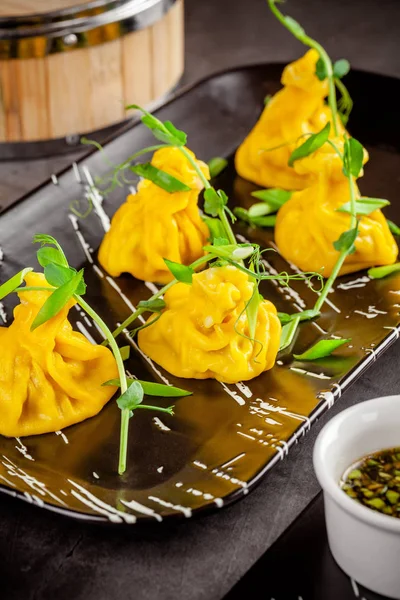 Concepto de cocina panasiática. Wontons de masa amarilla, carne picada. Albóndigas japonesas con carne picada. Sirve platos en el restaurante en un plato negro. Espacio de copia imagen de fondo —  Fotos de Stock