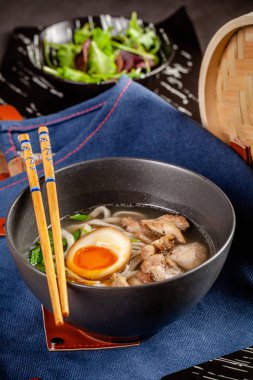 Pan-Asya Mutfağı kavramı. Japon Ramen Çin eriştesi, yumurta, tavuk ve yeşil soğan çorbası. Kabın içinde restoranda yemekler sunan. Arka plan görüntüsü. kopya alanı