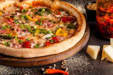 Konsept İtalyan mutfağı. Sebze ve jambon, pastırma ve parmesan peyniri ile gerçek bir pizza. Masadaki malzemeler. Masanın üstündeki bardakta kırmızı şarap. Closeup, arka plan görüntüsü