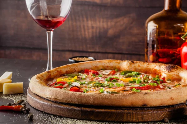 Concept Cuisine italienne. Une vraie pizza aux légumes et jambon, bacon et parmesan. Les ingrédients sur la table. Vin rouge dans un verre sur la table. Gros plan, image de fond — Photo
