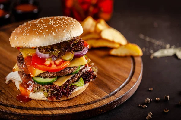 Koncepcja kuchni amerykańskiej. Duży domowy Burger z podwójnym paszteciem wieprzowym i cielęciny, pomidorem, ogórkiem, sałata i serem. Zbliżenie, obraz tła — Zdjęcie stockowe