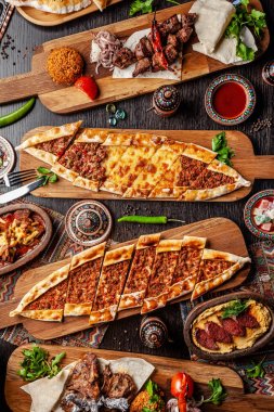 Geleneksel Türk mutfağı. Pizza, pide, pidesi, sucuk, Humus, kebap, Bulgar. Masada birçok yemek var. Restoranda yemekler servis edilir. Arka plan görüntüsü. Üst görünüm, düz yatıyordu