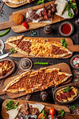 Traditional Turkish cuisine. Pizza, pita, pidesi, sucuk, hummus, kebab, bulgar. Many dishes on the table. Serving dishes in restaurant. Background image. Top view, flat lay clipart