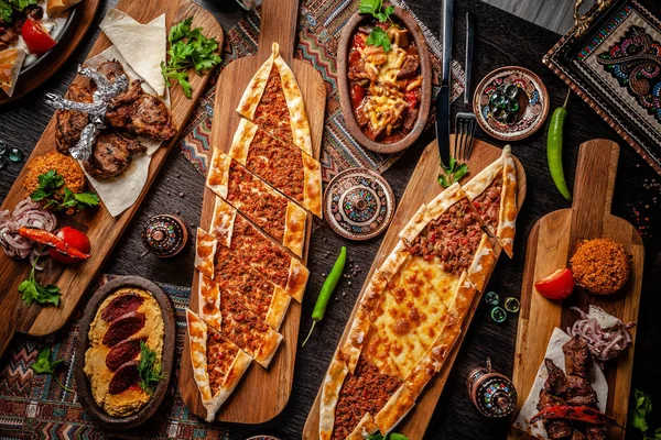 Geleneksel Türk mutfağı. Pizza, pide, pidesi, sucuk, Humus, kebap, Bulgar. Masada birçok yemek var. Restoranda yemekler servis edilir. Arka plan görüntüsü. Üst görünüm, düz yatıyordu