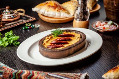 Geleneksel Türk, Arap mutfağı. Salamlı sosisli humus, kil tabakta, tahta bir masada. Beyaz bir tabakta. Restoranda yemek servisi. kopyalama alanı