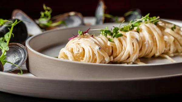 Az olasz konyha fogásait. Tészta tejszínes mártással, pesto és tenger gyümölcsei, kagyló. Európai konyhát. Az étterem mikrozöld ételeket szolgál fel. másolási tér — Stock Fotó