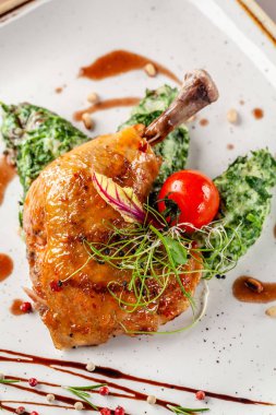 Bir Japon restoranında akşam yemeği konsepti. Ispanak baharatlı bir sos krema ve sırlı tavuk bacakları ile süsleyin. Bardakta erik şarabı. Arka plan görüntüsü. kopyalama alanı