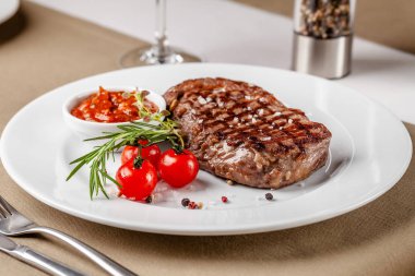 Amerikan mutfağı. Kırmızı barbekü domates sosu ve kiraz domates ile Sığır biftek. Bir bardak soğuk şarap. Restoranda beyaz tabakta yemek servisi. Arka plan görüntüsü. kopyalama alanı