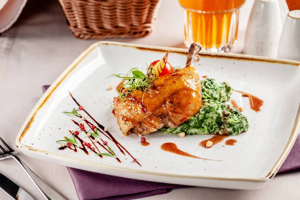 The concept of dinner in a Japanese restaurant. Spinach garnish with cream and glazed chicken legs in a spicy sauce. Plum wine in a glass. Background image. copy space