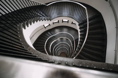 Büyük binanın sarmal merdivenlerinin derinliklerine bakıyorum.